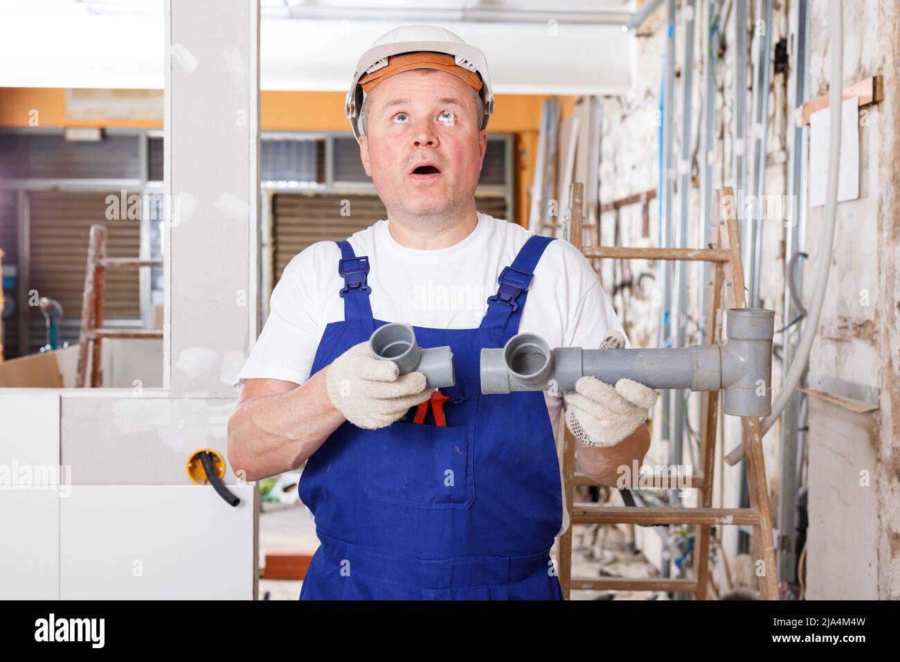 Puzzled builder with plastic pipes Stock Photo - Alamy