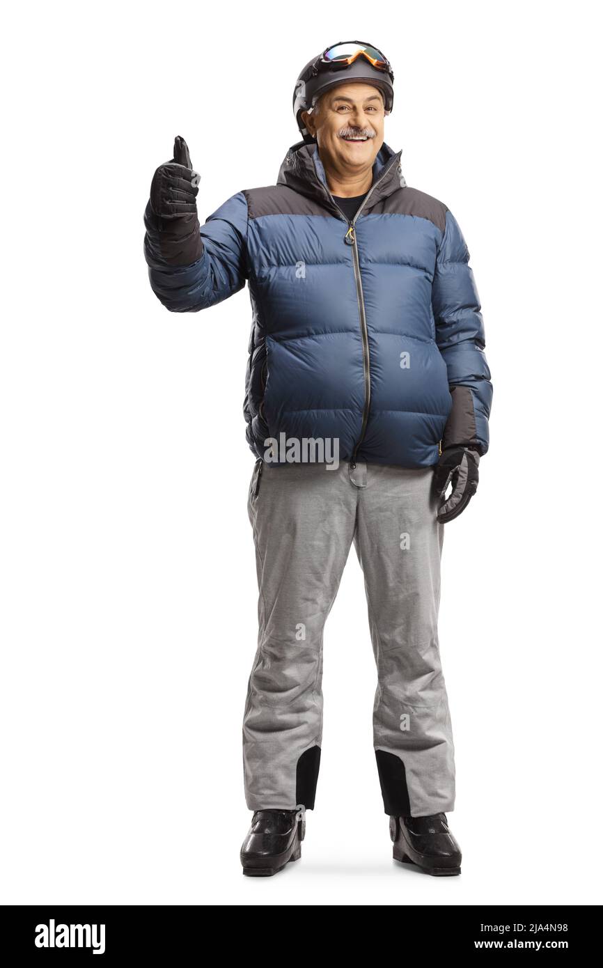 Full length portrait of a mature man in a winter jacket skiing boots and helmet showing thumbs up isolated on white background Stock Photo