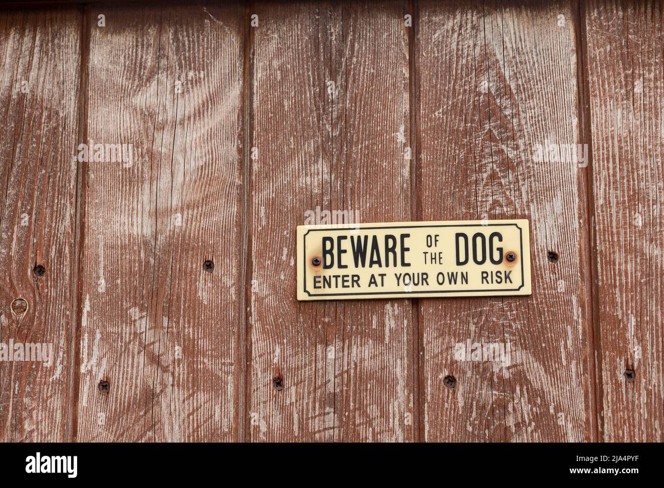 A beware of the dog sign on a wooden fence. Stock Photo