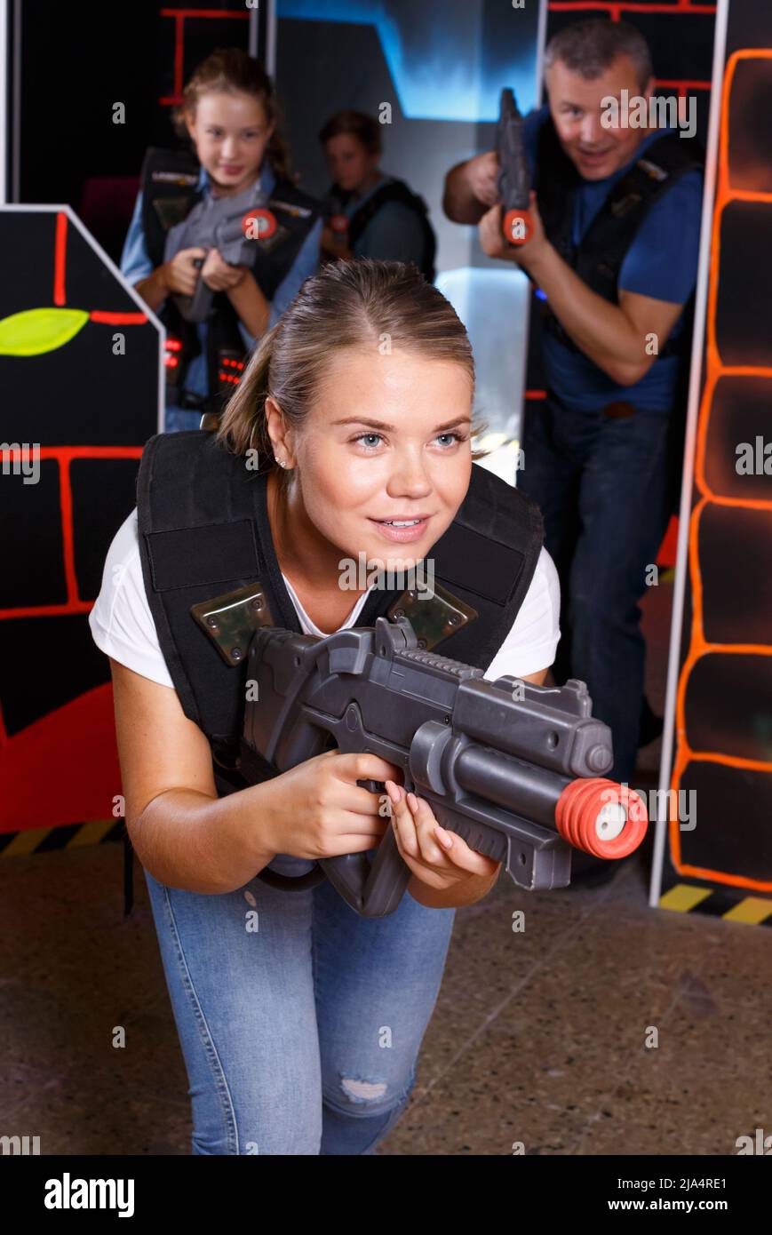 Young woman holding laser gun and playing lasertag game with family