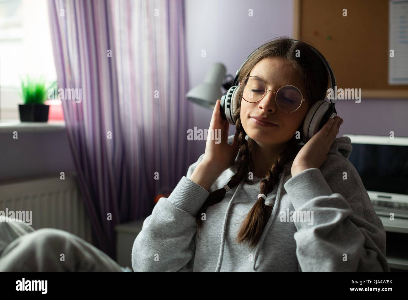 A teenage girl listens to music on wireless headphones with her eyes ...