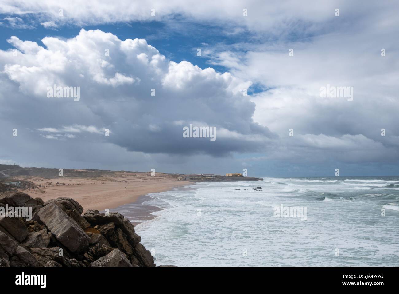 Large and numerous Atlantic Oceas waves rolling into the rocky coastline by Guincho Beach - Praia do Guincho with dramatic clouds in the sky against t Stock Photo