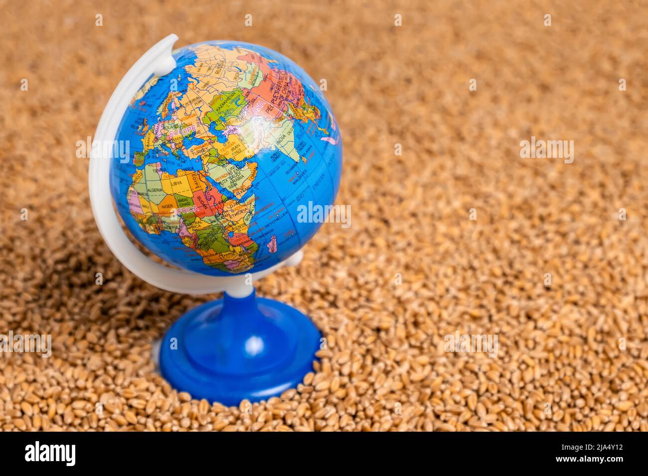 World globe on wheat grain pile as background. Concept of food shortage, grain supply crisis and global food scarcity Stock Photo