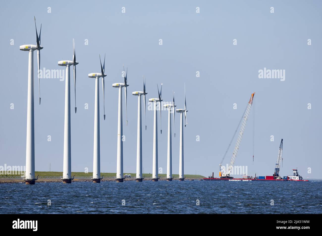 Lelystad, The Netherlands - April 22, 2022: Crane ship and supply vessel busy with demolition offshore wind turbine farm Stock Photo