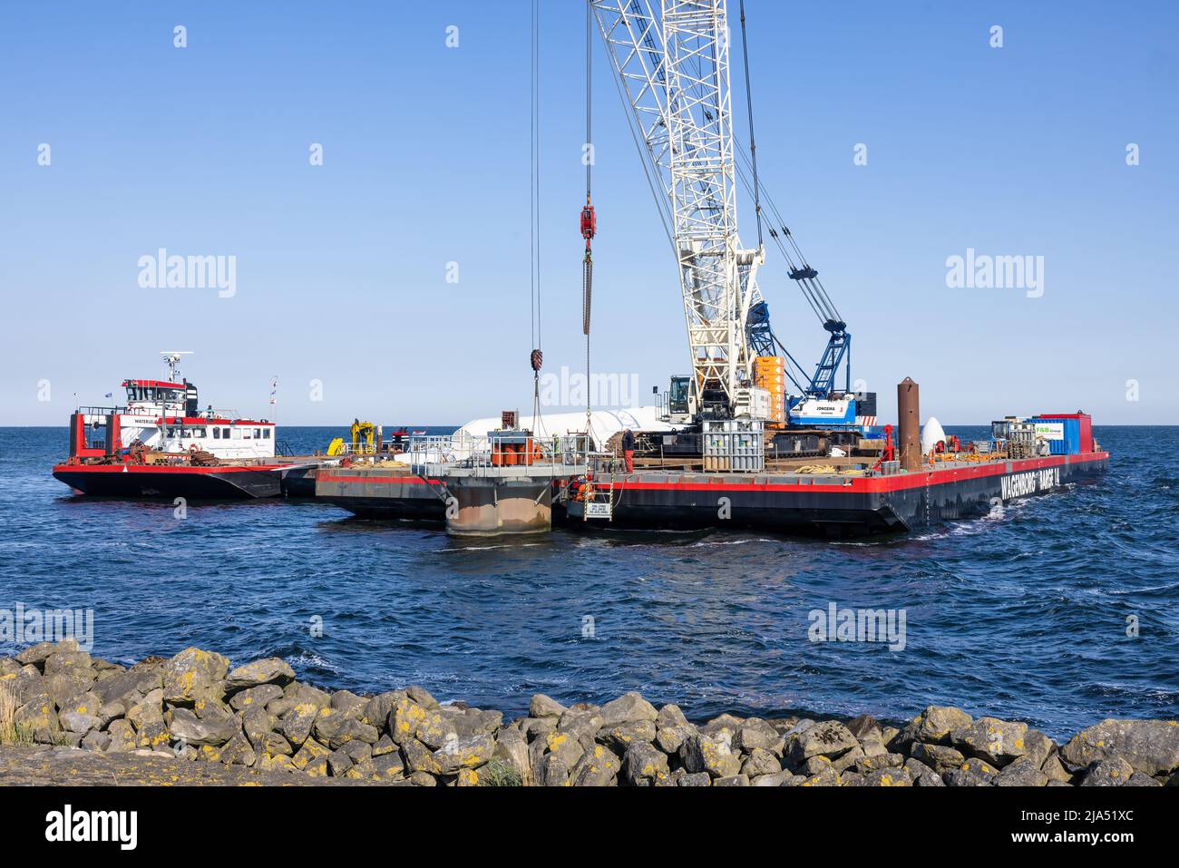 Lelystad, The Netherlands - April 22, 2022: Crane ship and supply vessel busy with demolition old offshore wind turbine Stock Photo
