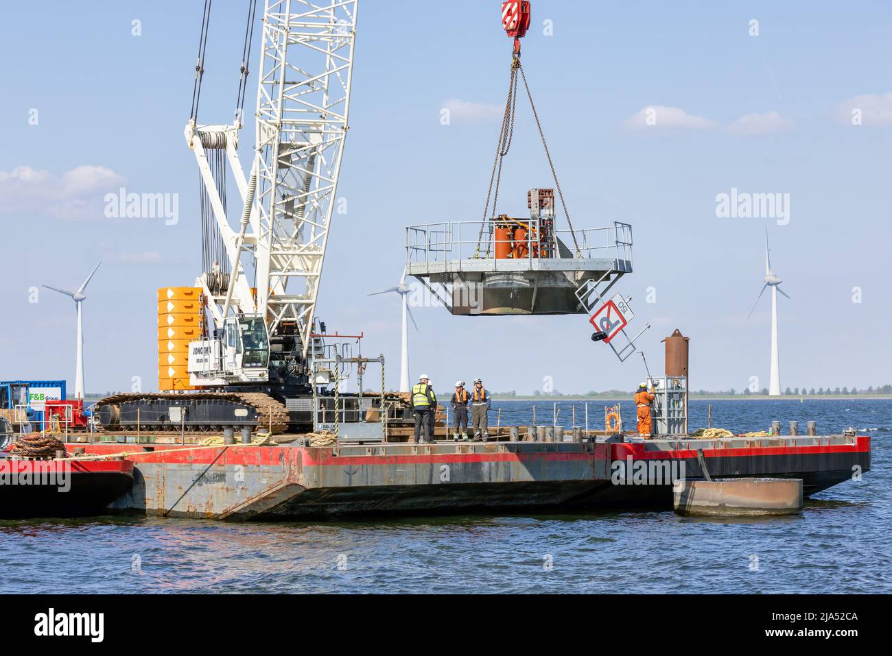 Lelystad, The Netherlands - April 22, 2022: Crane ship lifting foundation by demolition old offshore wind turbine Stock Photo