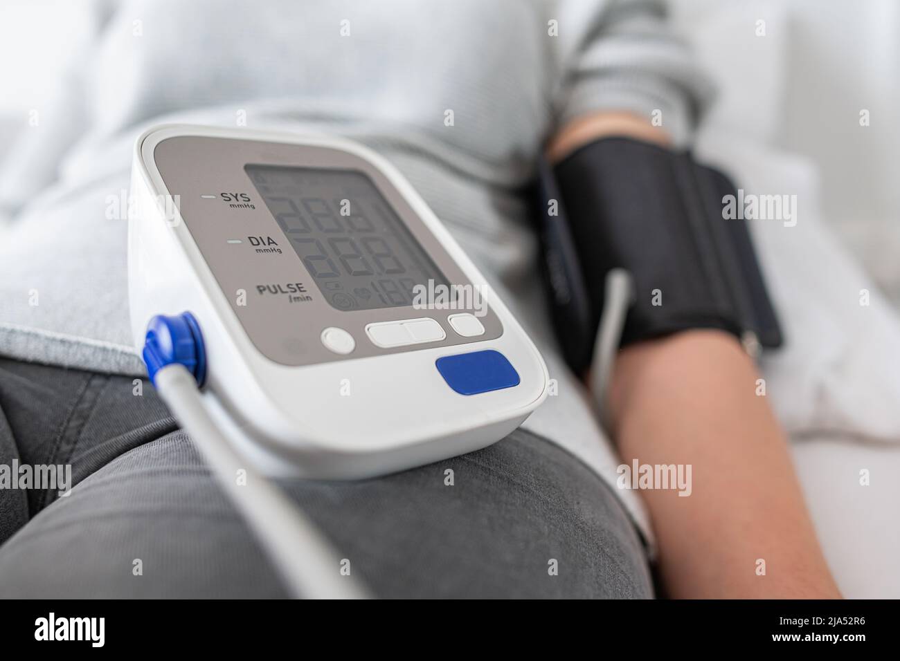 A woman is testing her blood pressure while lying in bed. Stock Photo