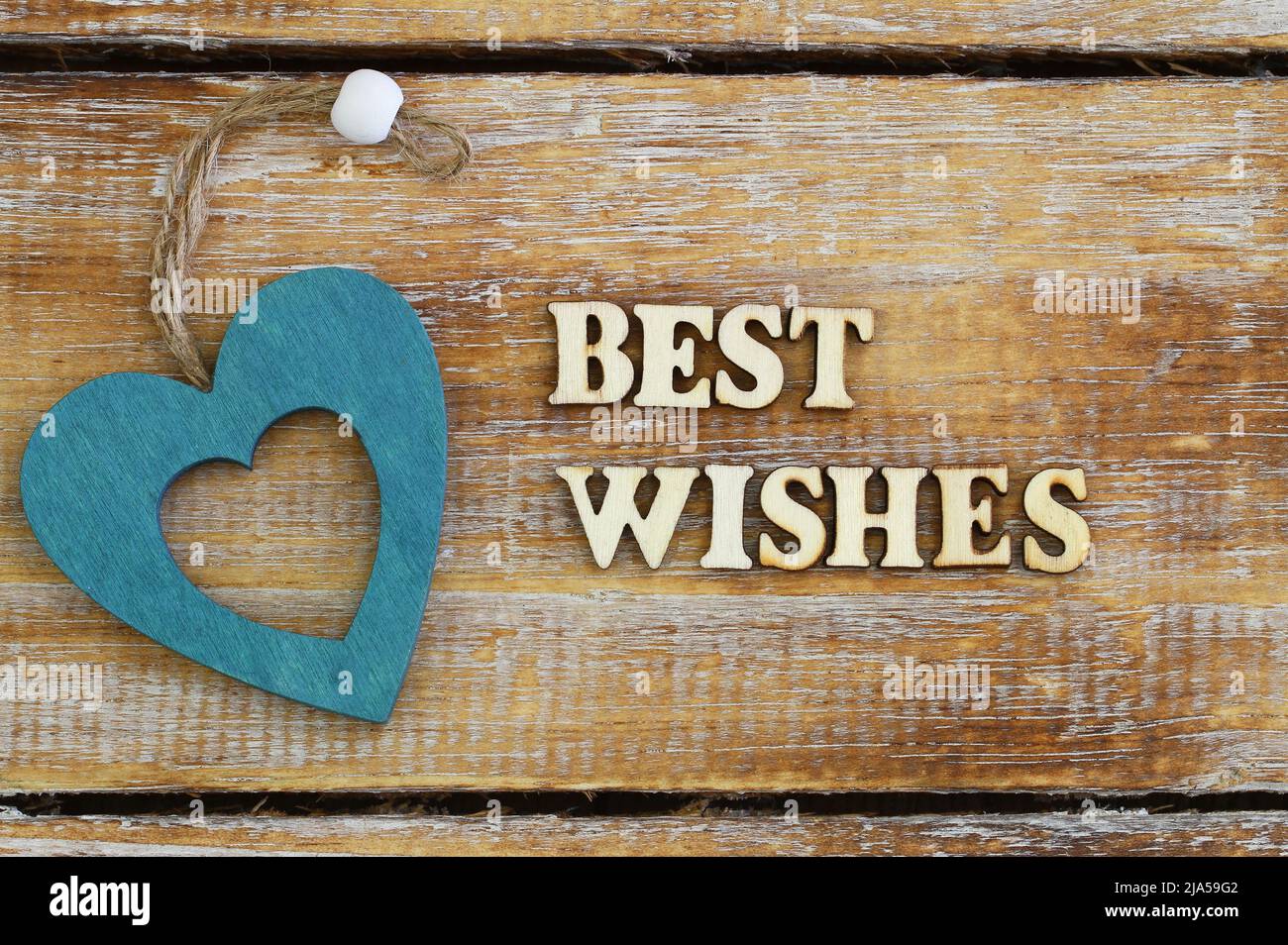 Best wishes written with wooden letters on rustic surface and a wooden heart Stock Photo