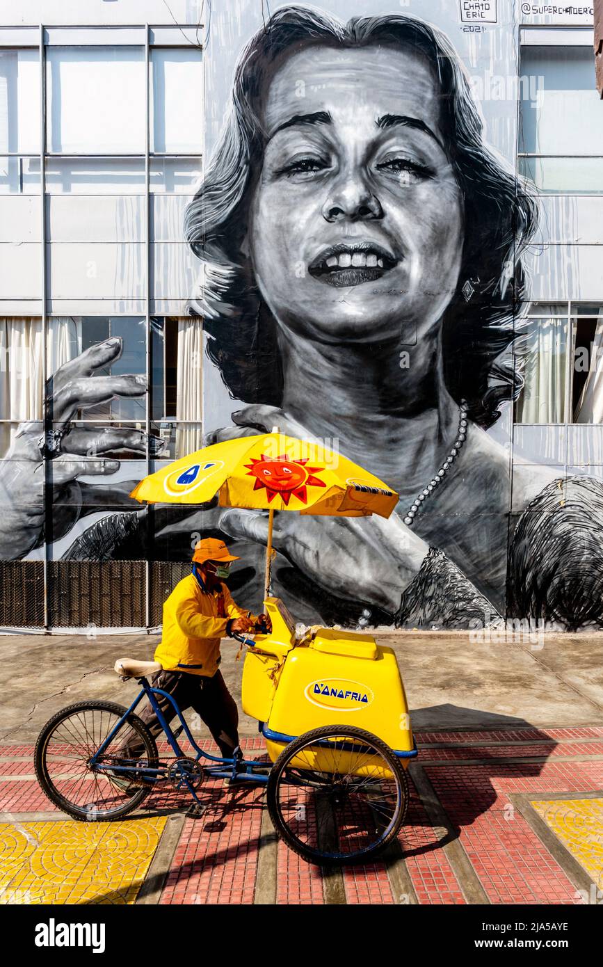 An Ice Cream Seller Passes By A Large Wall Mural In The Barranco District, Lima, Peru. Stock Photo