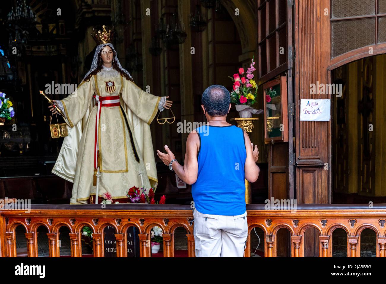 Local People Pass By and Pray To A Statue Of The Virgin Mary At The Minor Basilica and Convent of Nuestra Señora de la Merced, Central Lima, Peru. Stock Photo