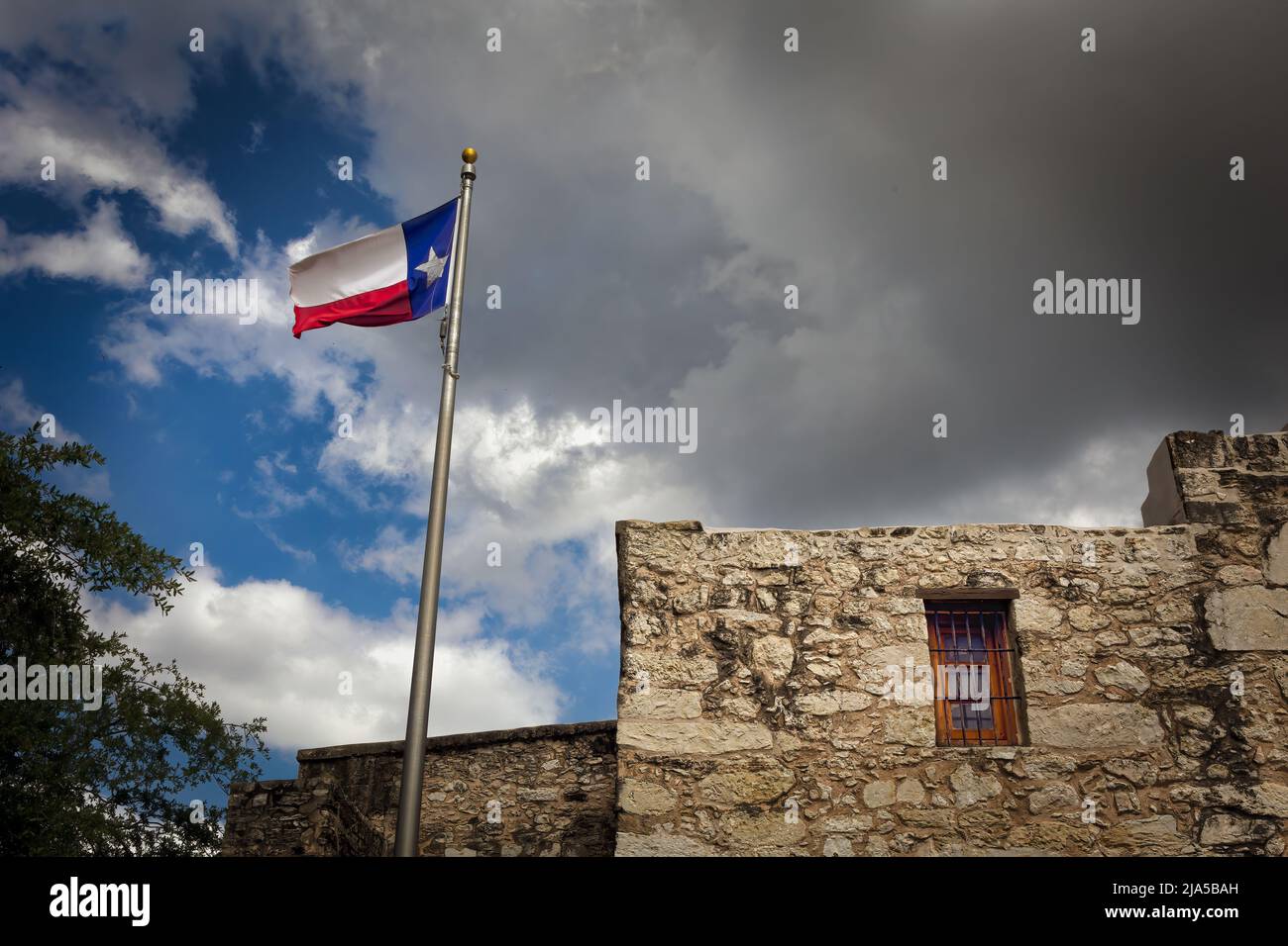 The Lonestar flag flies over the Alamo, originally called Mission San Antonio de Valero, and now a National Historic Landmark in downtown San Antonio, Stock Photo