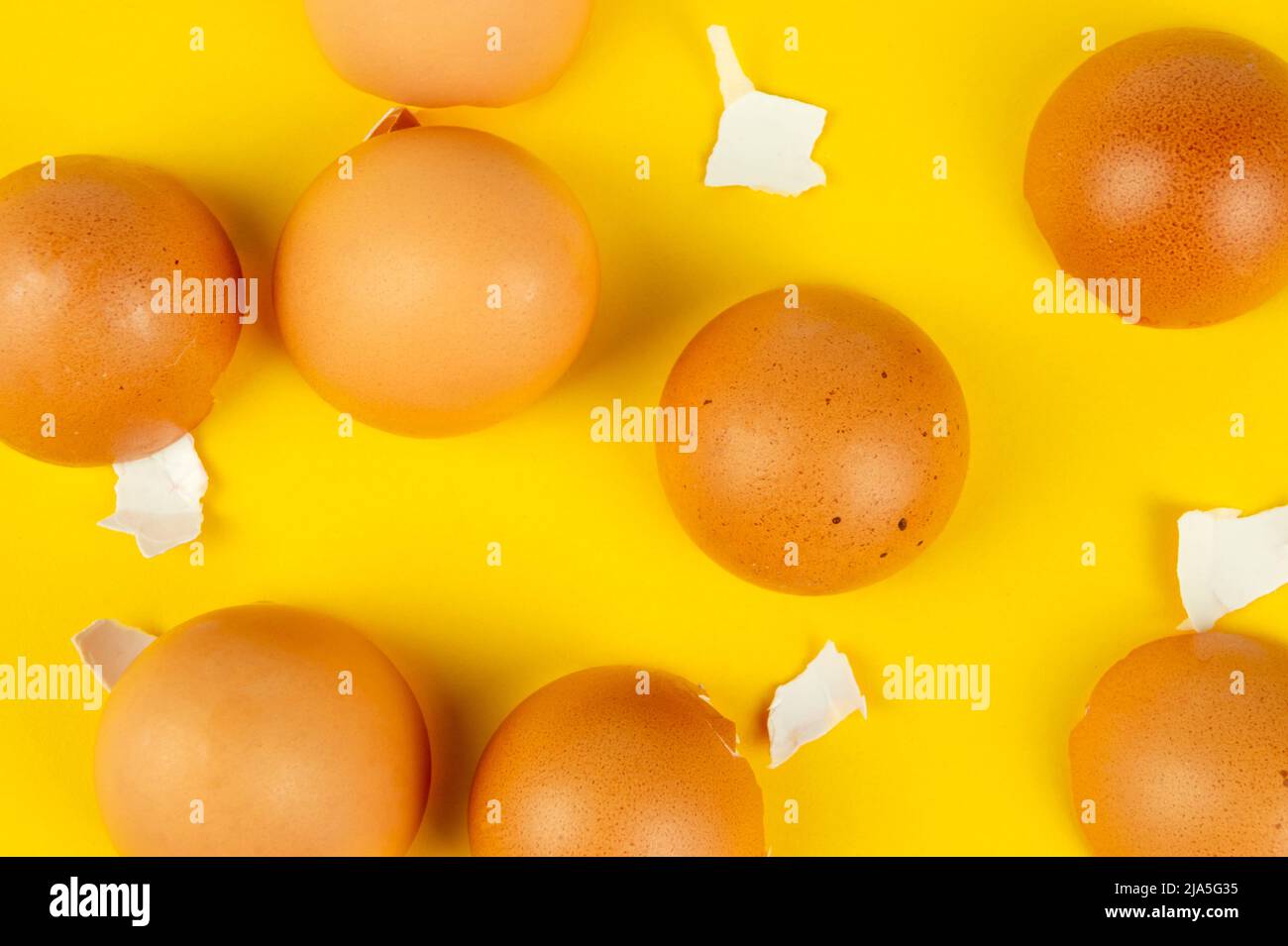 Many brown broken eggshells on yellow background top view Stock Photo