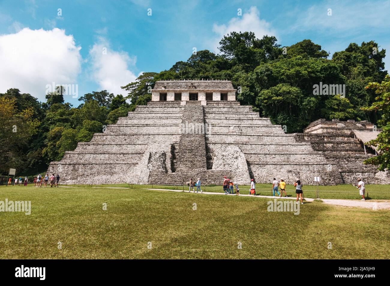 tourists walk past Temple of the Inscriptions, the largest ancient Mayan pyramid at the Palenque Archaeological Zone in the state of Chiapas, Mexico Stock Photo