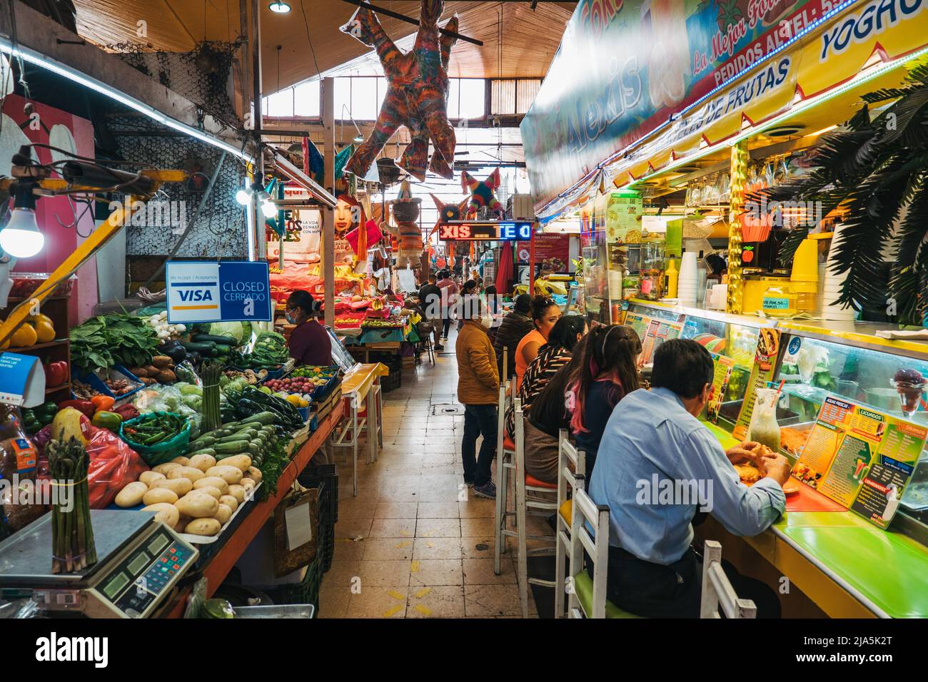 Patrons explore the various fresh produce and hot food vendors inside the Coyoacan Market in Mexico City, Mexico Stock Photo
