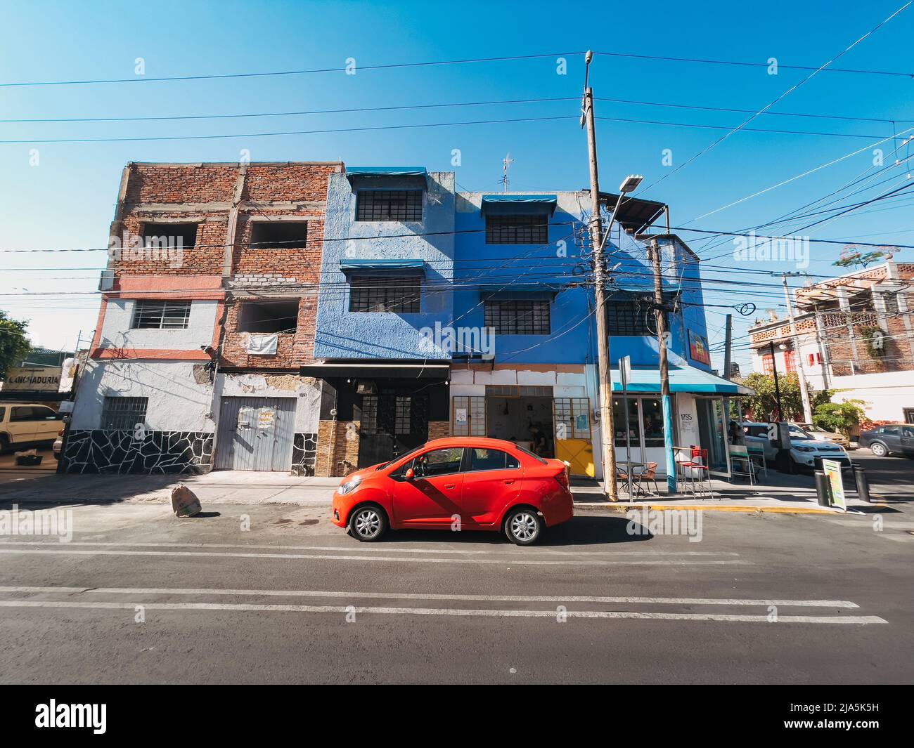 a red sedan parked outside a three-story apartment block in the city of Guadalajara, Jalisco, Mexico Stock Photo