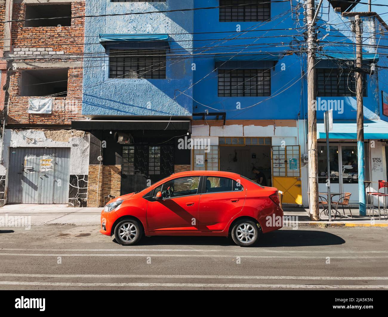 a red sedan parked outside a three-story apartment block in the city of Guadalajara, Jalisco, Mexico Stock Photo