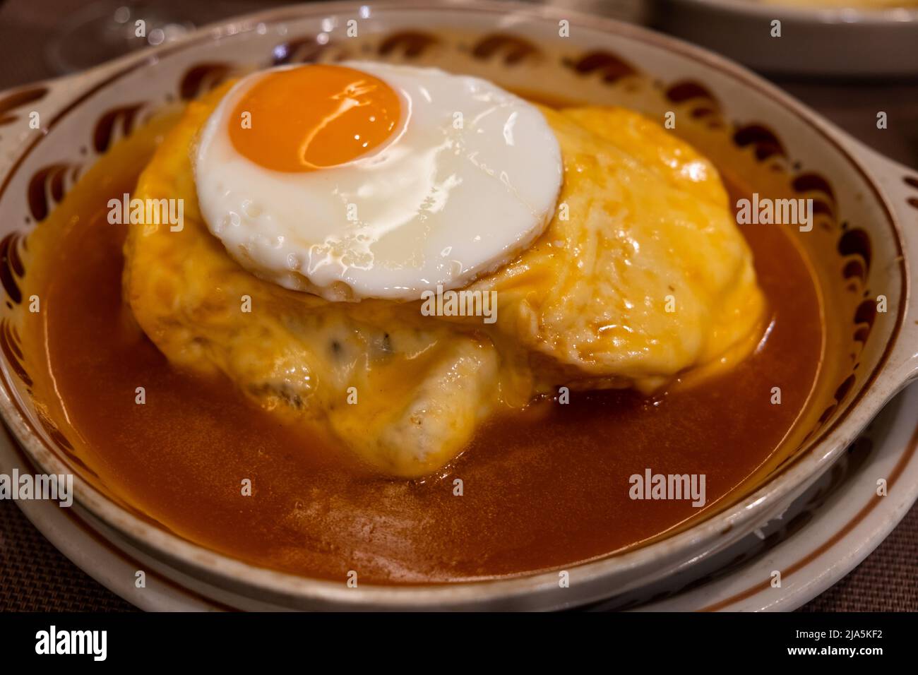 Top view of a fried egg on top of the - ' francesinha ' - a typical dish of the city of Porto, Portugal. Typical Food, Oporto, Portugal. Stock Photo