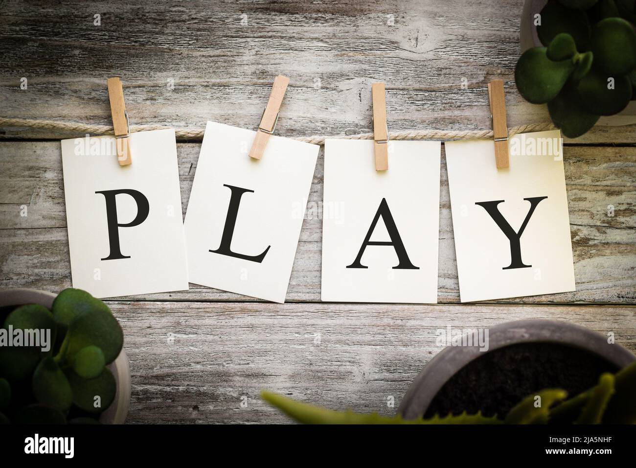 A set of printed cards spelling the word PLAY on an aged wooden