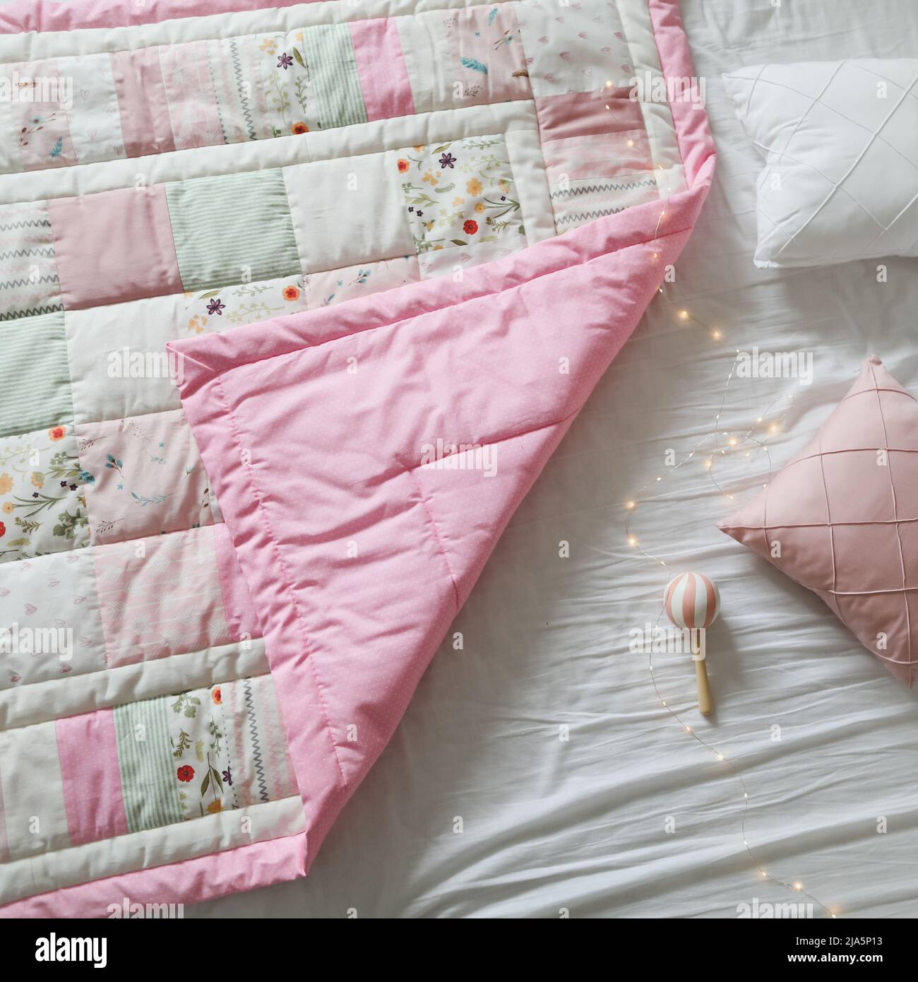 Cozy baby cot with a patchwork blanket. Baby bedding and textile for nursery Stock Photo