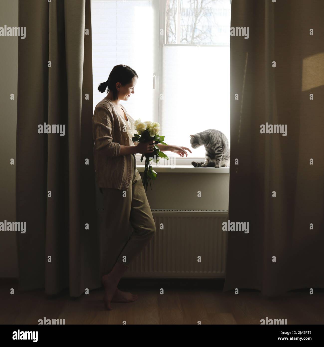 Indoor portrait of young woman playing with cat at home Stock Photo