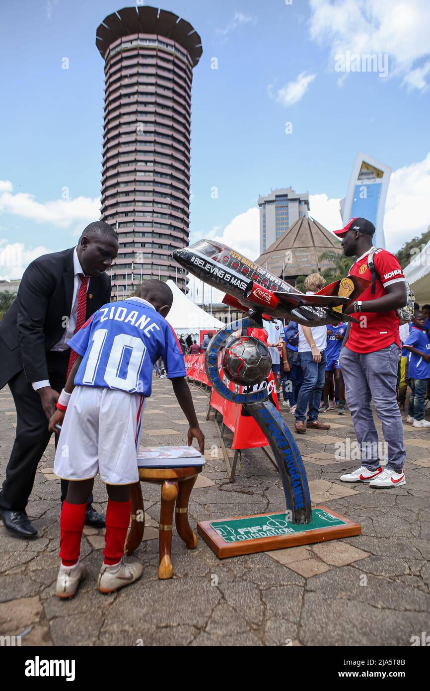 A Kenyan soccer fan and his son displays a sculpture depicting a plane