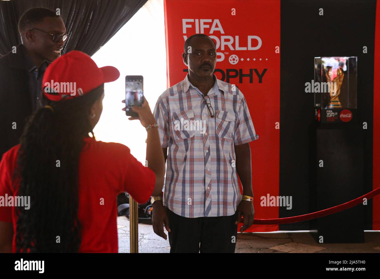 A Kenyan soccer fan takes a photo with the FIFA World Cup (R) during