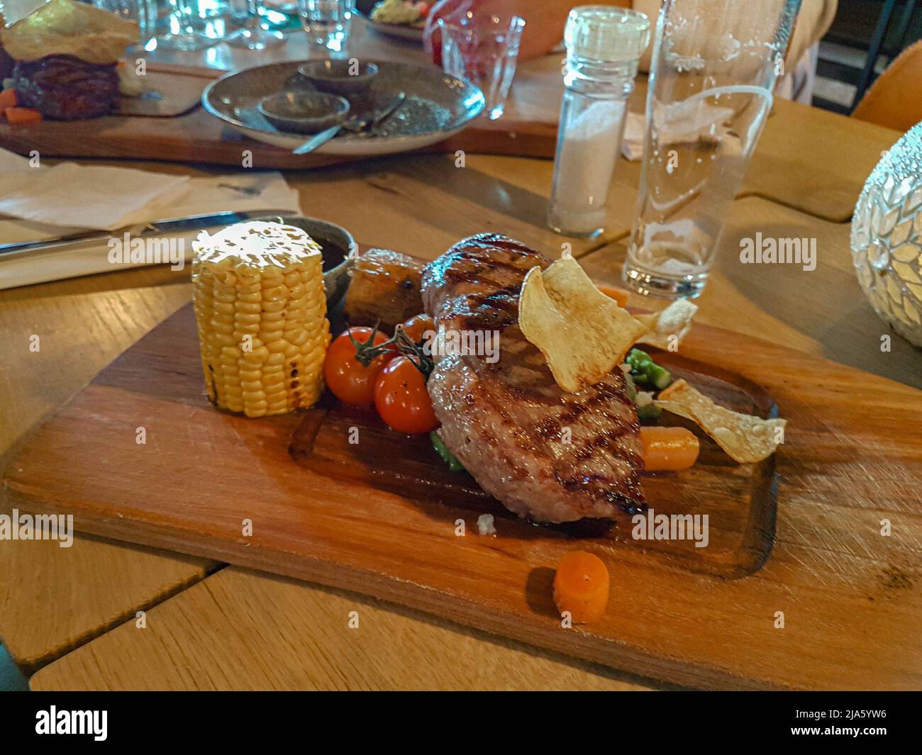 Sirloin entrocote steak with vegetable garnish on a luxury wooden plank board served in a restaurant Stock Photo