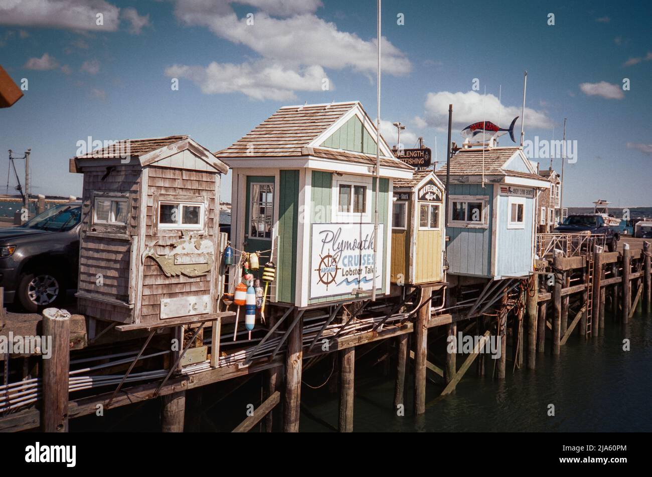 Colorful ocean cruse vendor shacks lined up on the docks in Plymouth Harbor. Plymouth Massachusetts. The image was captured on analog color film. Stock Photo