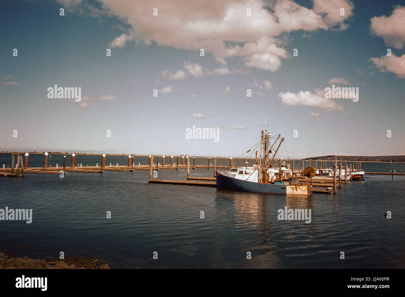 A fishing boat births in otherwise empty commercial docks in Plymouth Harbor. Plymouth Massachusetts. The image was captured on analog color film. Stock Photo