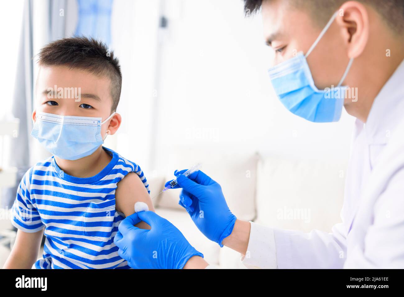 Medical Doctor injecting child with vaccine at clinic or hospital Stock Photo