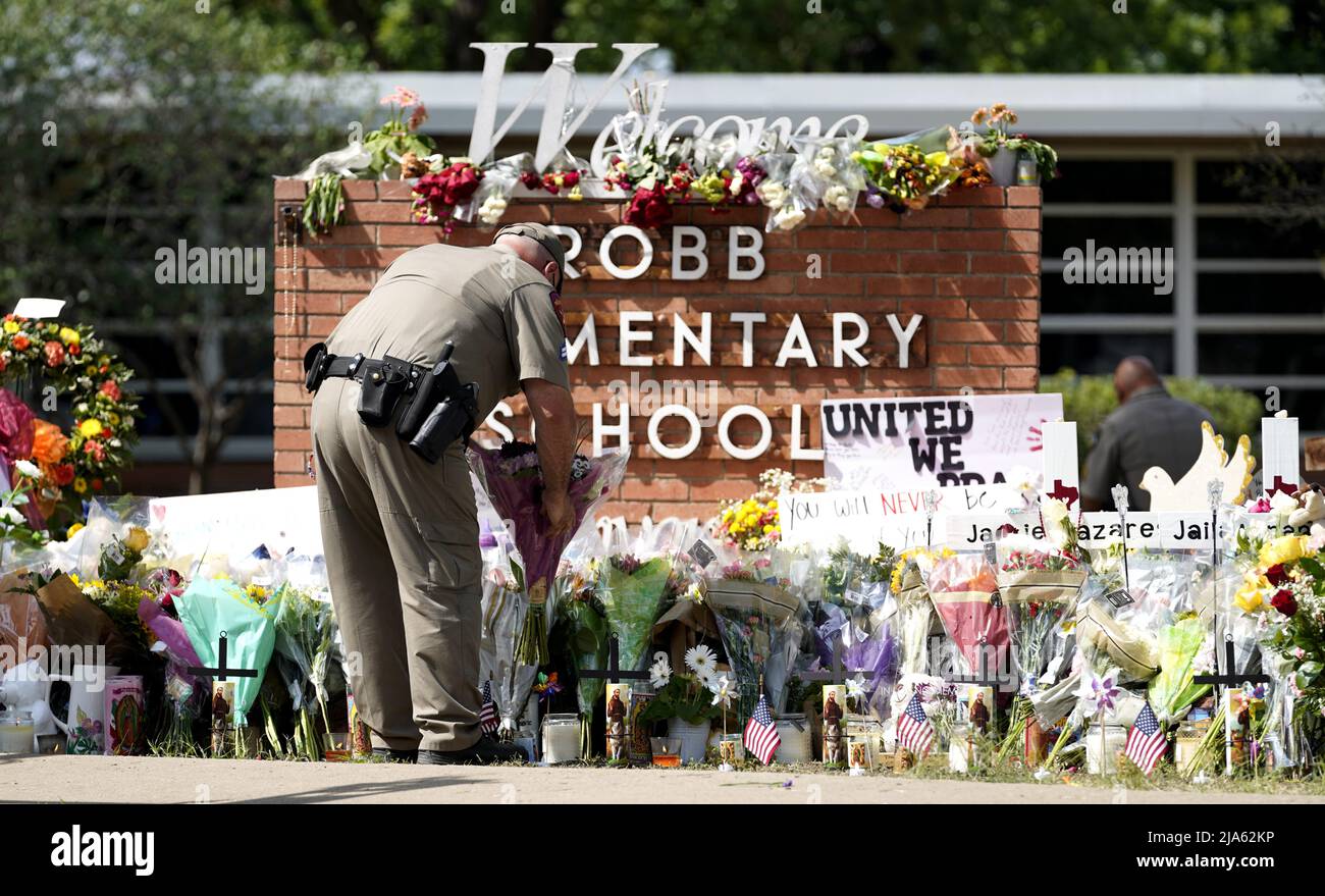 Uvalde, USA. 27th May, 2022. A police officer lays flowers outside Robb Elementary School in the town of Uvalde, Texas, the United States, May 27, 2022. At least 19 children and two adults were killed in a shooting at Robb Elementary School in the town of Uvalde, Texas, on Tuesday. Credit: Wu Xiaoling/Xinhua/Alamy Live News Stock Photo
