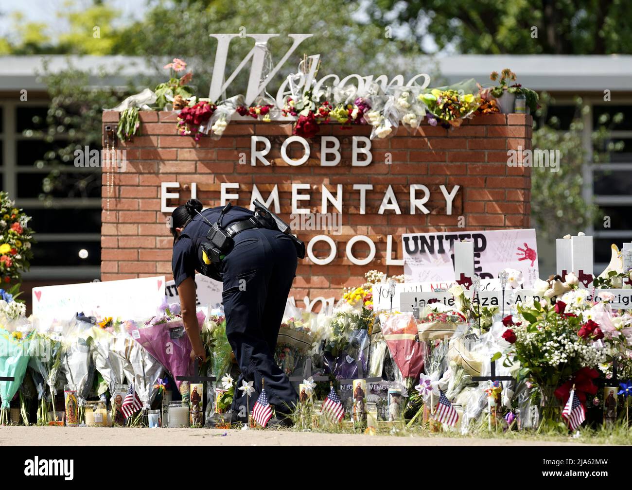 Uvalde, USA. 27th May, 2022. A police officer lays flowers outside Robb Elementary School in the town of Uvalde, Texas, the United States, May 27, 2022. At least 19 children and two adults were killed in a shooting at Robb Elementary School in the town of Uvalde, Texas, on Tuesday. Credit: Wu Xiaoling/Xinhua/Alamy Live News Stock Photo