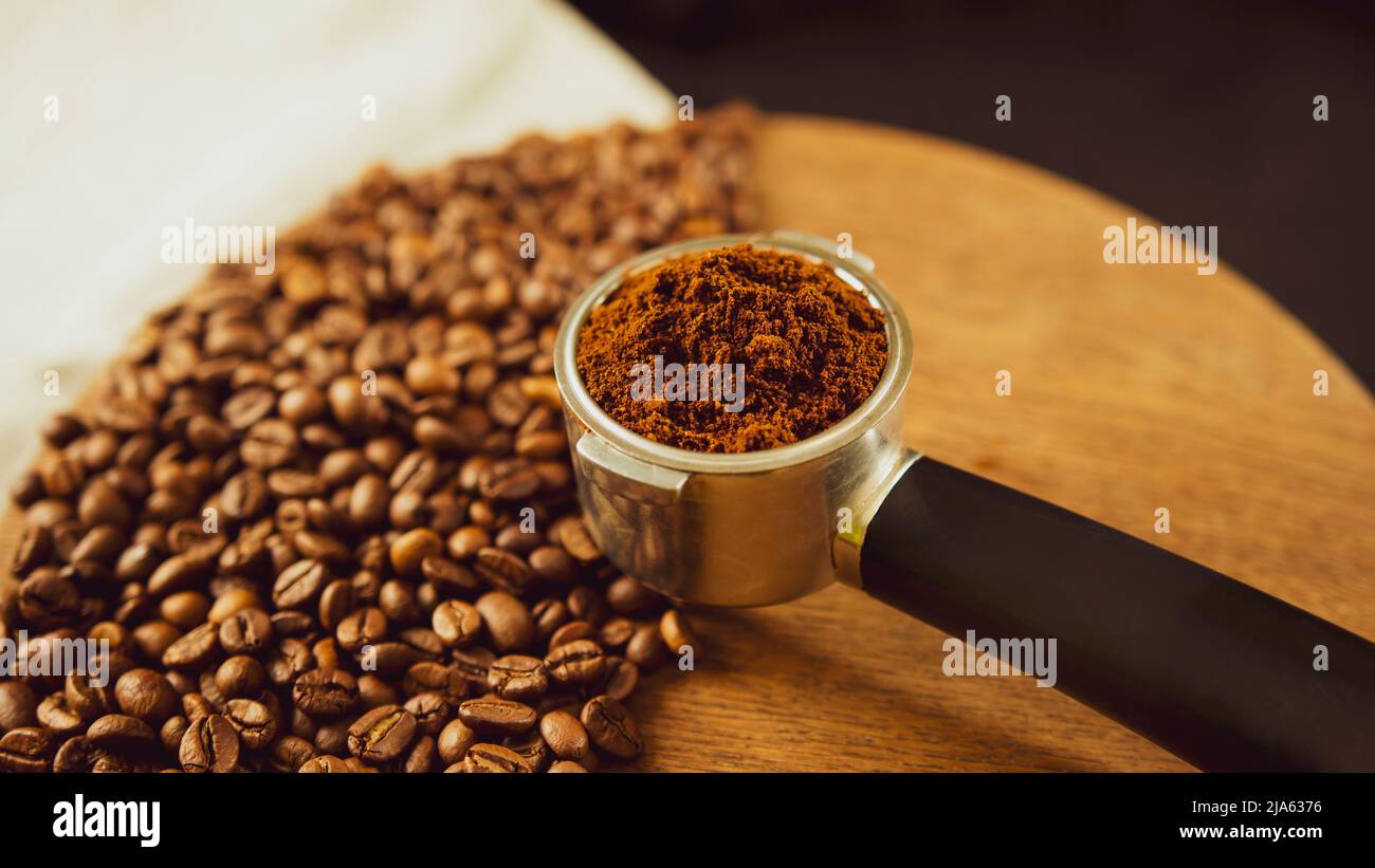 Ground coffee in portafilter on wooden board with coffee beans. Freshly