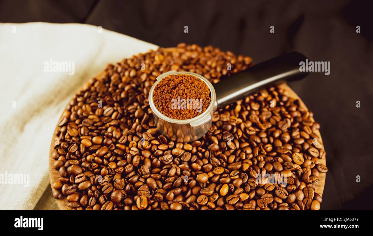 Ground coffee in portafilter on wooden board with coffee beans. Freshly ground coffee in filter