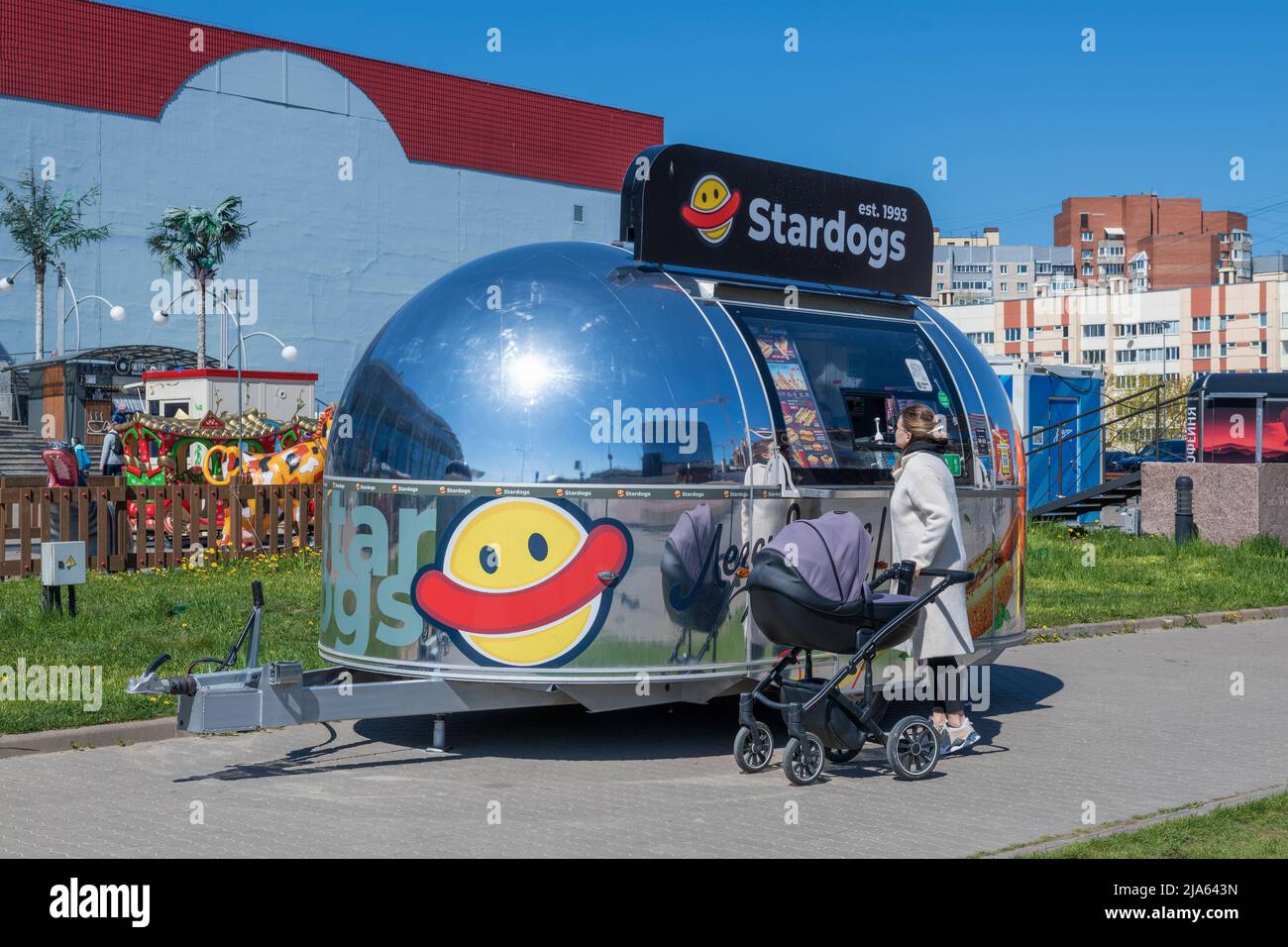 SAINT PETERSBURG, RUSSIA - MAY 22, 2022: A young woman with a baby carriage an order in a food truck Stock Photo