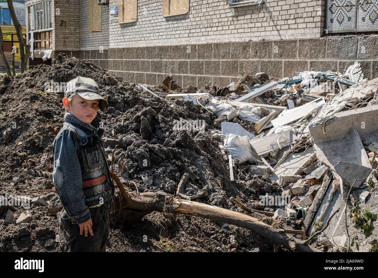 Bakhmut, Ukraine. 24th May, 2022. A child stands in front of a residential building destroyed by Russian artillery strikes in Bakhmut, Donbas. As Bakhmut stands as a key city to Ukrainian forces in defending Donetsk(Donbas) region, the city is under attack by the Russian troops. The Russian invasion of Ukraine started on February 24, the war that has killed numerous civilians and soldiers. Credit: SOPA Images Limited/Alamy Live News Stock Photo