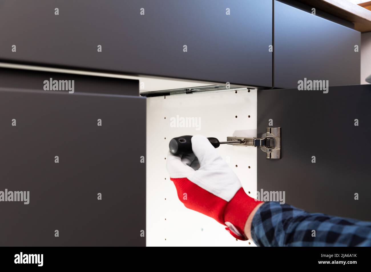 Handyman after installing door with screwdriver testing in kitchen. Smooth and slowly closing. Home improvement by a professional craftsperson. Stock Photo