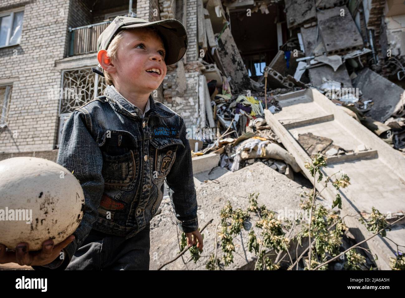 Bakhmut, Ukraine. 24th May, 2022. A child is playing in front of the ruins of the residential building destroyed by Russian artillery strikes in Bakhmut, Donbas. As Bakhmut stands as a key city to Ukrainian forces in defending Donetsk(Donbas) region, the city is under attack by the Russian troops. The Russian invasion of Ukraine started on February 24, the war that has killed numerous civilians and soldiers. (Photo by Alex Chan Tsz Yuk/SOPA Images/Sipa USA) Credit: Sipa USA/Alamy Live News Stock Photo