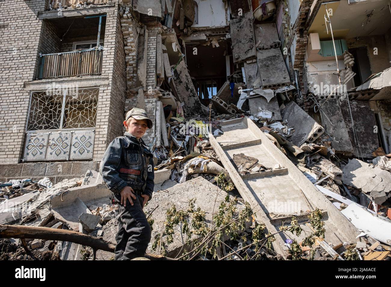 Bakhmut, Dontesk Oblast, Ukraine. 24th May, 2022. A child stands in front of a residential building destroyed by Russian artillery strikes in Bakhmut, Donbas. As Bakhmut stands as a key city to Ukrainian forces in defending Donetsk(Donbas) region, the city is under attack by the Russian troops. The Russian invasion of Ukraine started on February 24, the war that has killed numerous civilians and soldiers. (Credit Image: © Alex Chan Tsz Yuk/SOPA Images via ZUMA Press Wire) Stock Photo