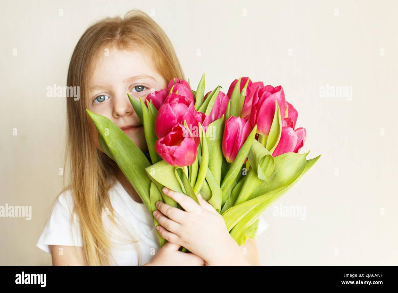portrait of a happy smiling litlle girl with bouquet of flowers tulips in her hands Stock Photo