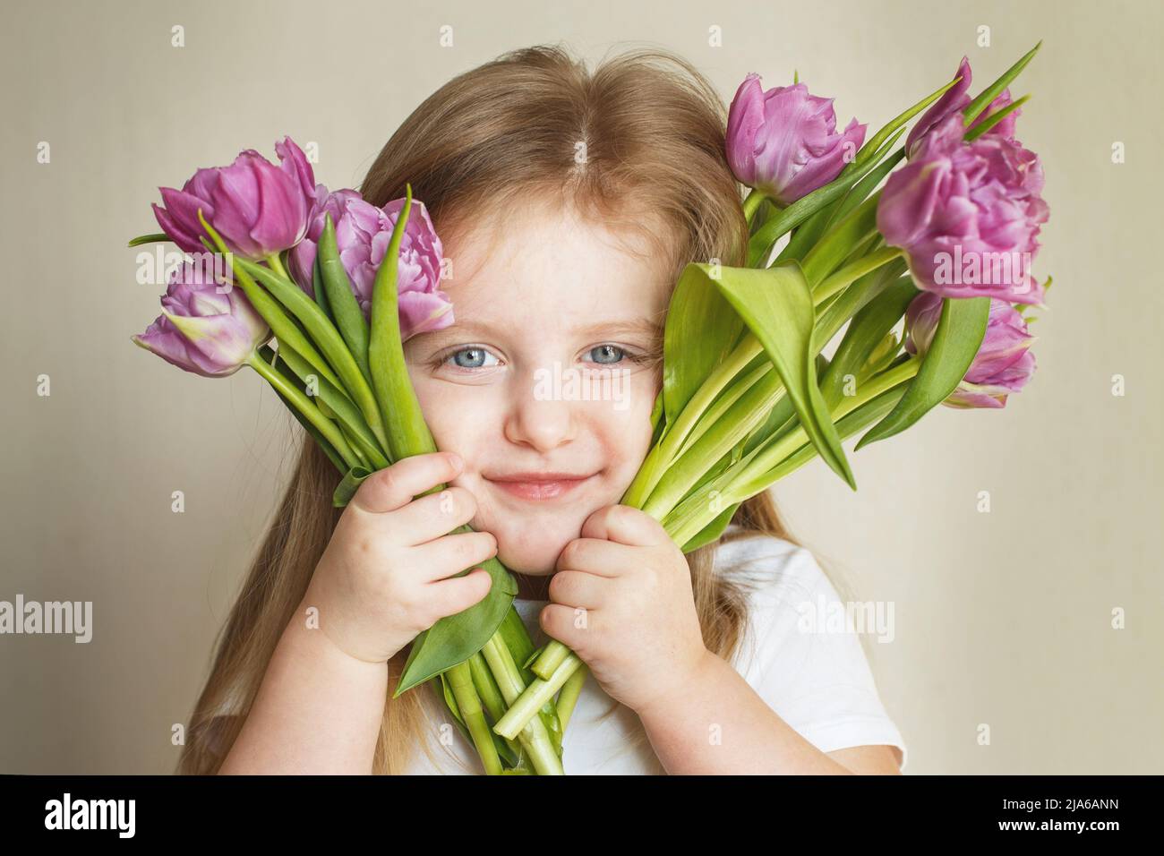 portrait of a happy smiling litlle girl with bouquet of flowers tulips in her hands Stock Photo