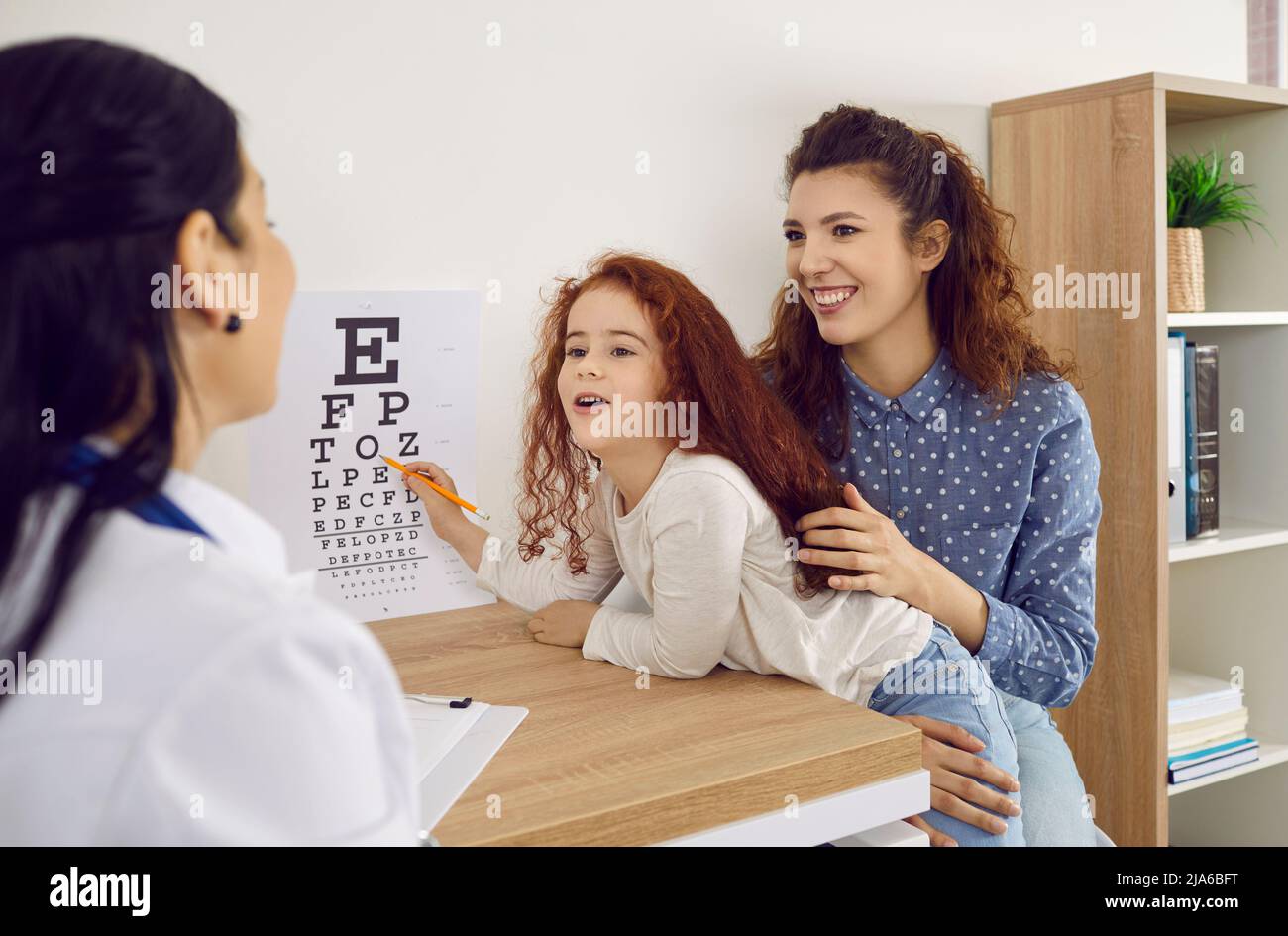 Mother with little daughter checks her child's vision at ophthalmology hospital. Stock Photo