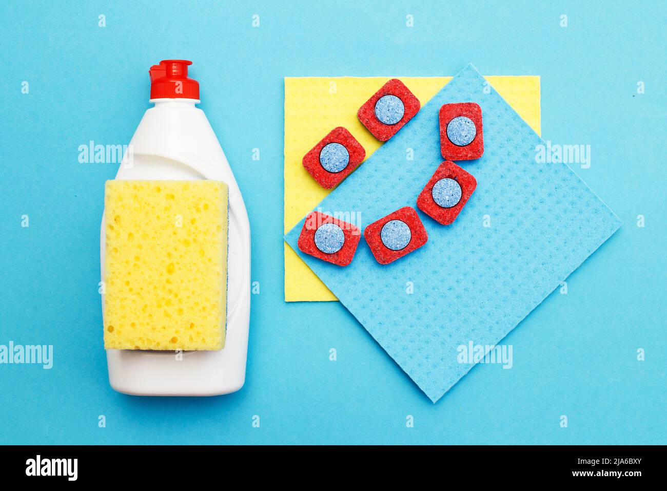 capsules for dishwashers, dishwashing detergents liquid, kitchen rag and sponges on a blue background. flat lay Stock Photo