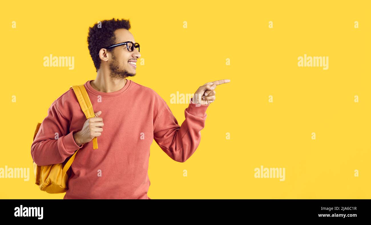 Happy black college or university student pointing finger to side at copy space background Stock Photo