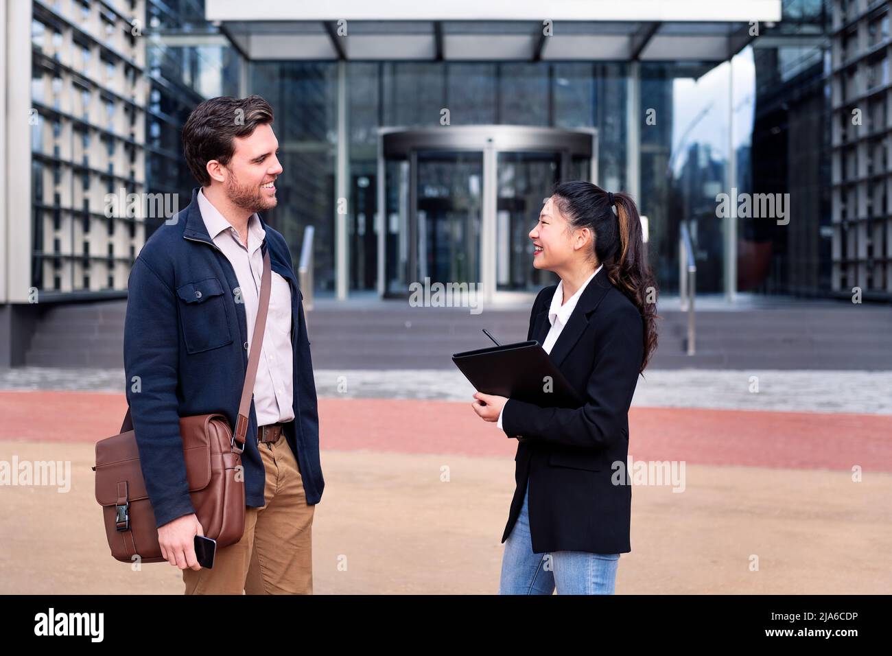 man and smiling asian woman talking about business Stock Photo