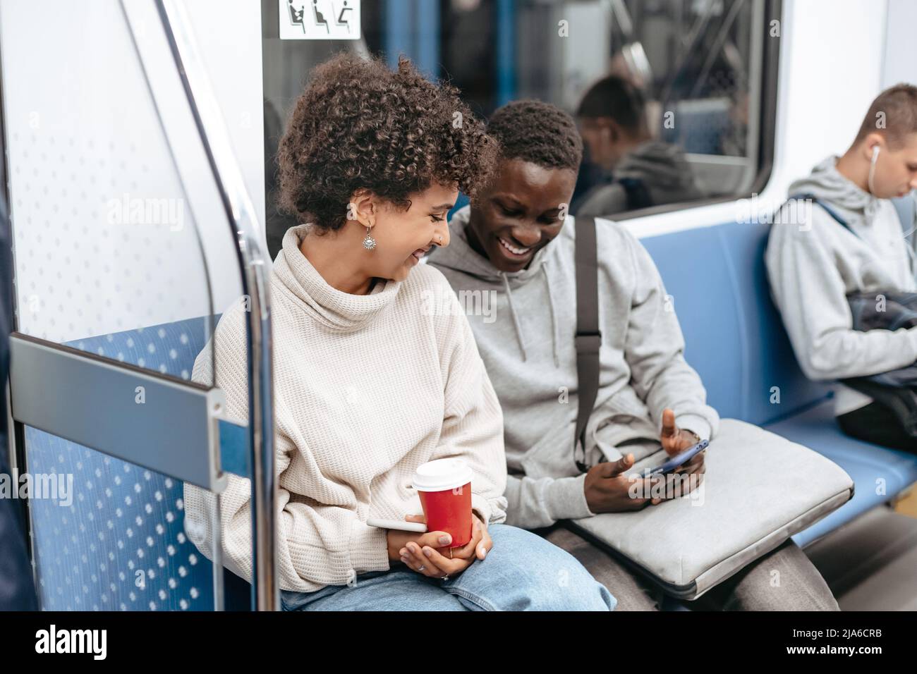 young couple using a smartphone while sitting in a subway car . Stock Photo