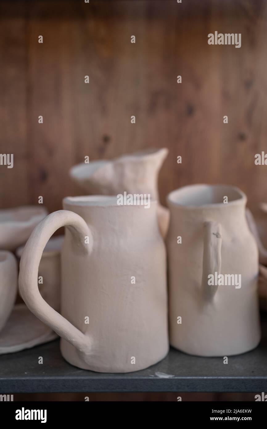 Ready-made ceramic dishes, handmade jugs on a shelf or shop window. Stock Photo