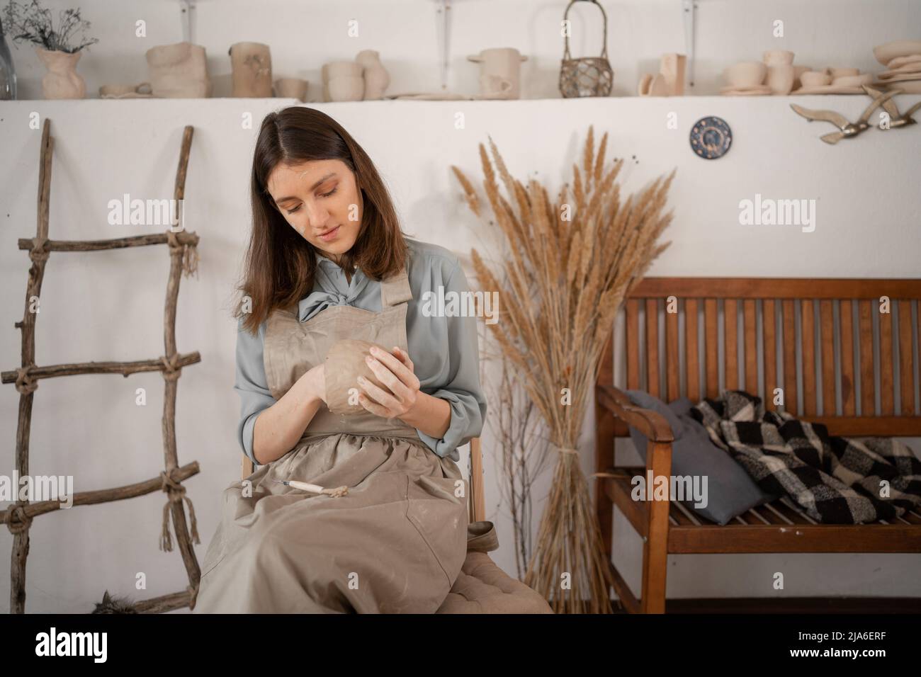 woman artist sculpts from wet clay in studio. ceramist makes handicrafts from ceramics. female industriousness concept. Stock Photo