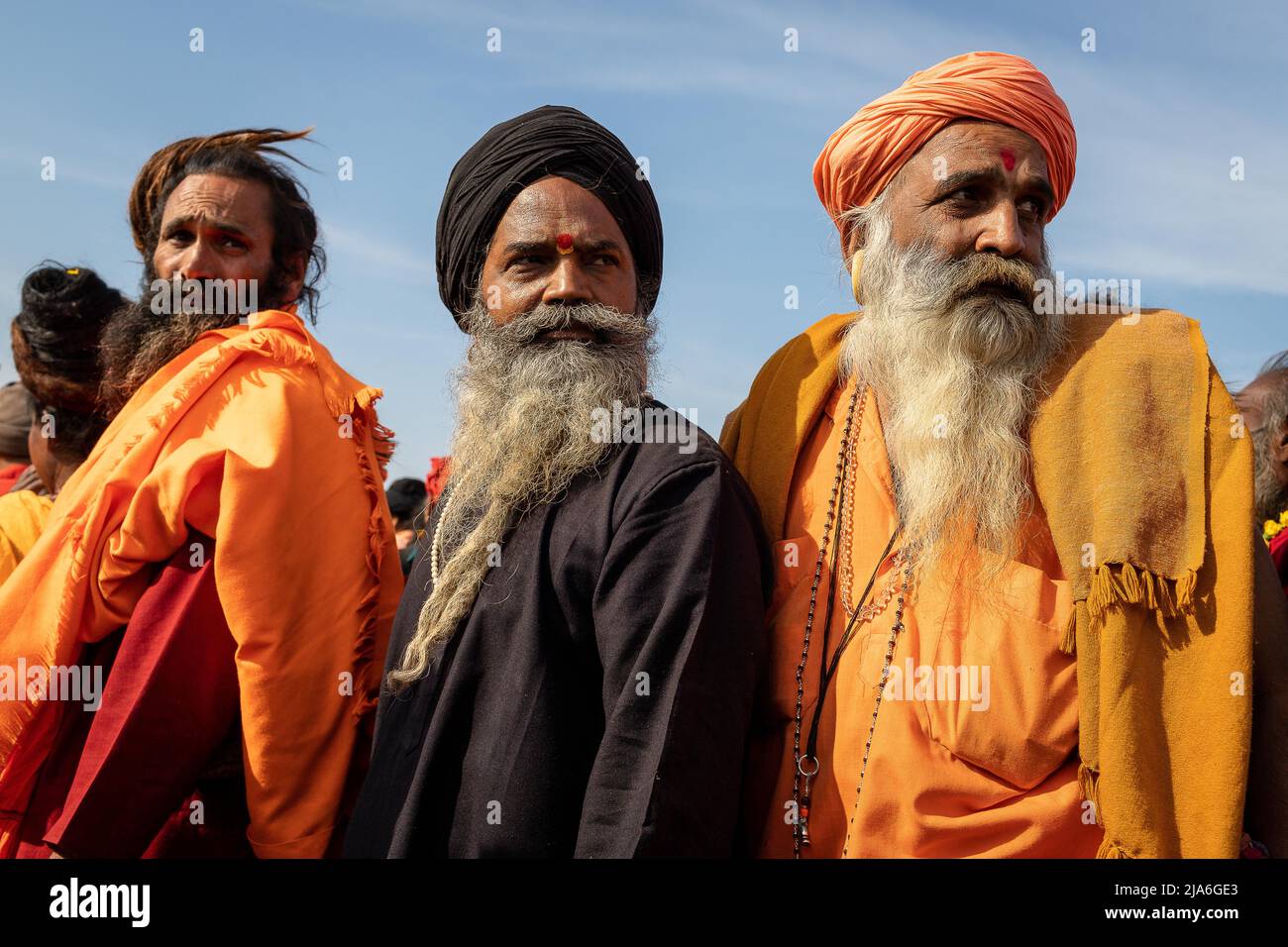 Sadhus looking backwords during the procession to the holy Ganges river during the Kumbh Mela. Every twelve years, millions of Hindu devotees begin a massive pilgrimage to the most sacred of Indian festivals: the Kumbha Mela, which takes place in Prayagraj, a place considered particularly auspicious because it is at the confluence of the Ganges, Yamuna and the mythical Saraswati. It is estimated that in 2019, 120 million people attended the sacred enclosure over the course of a month and a half. These numbers, equivalent to the total population of Japan, and 40 times the number of pilgrims who Stock Photo