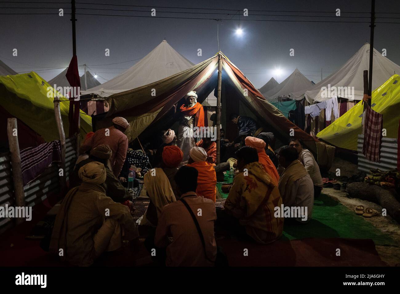 Sadhus meet outside of one of their tents during the Kumbh Mela festival. Every twelve years, millions of Hindu devotees begin a massive pilgrimage to the most sacred of Indian festivals: the Kumbha Mela, which takes place in Prayagraj, a place considered particularly auspicious because it is at the confluence of the Ganges, Yamuna and the mythical Saraswati. It is estimated that in 2019, 120 million people attended the sacred enclosure over the course of a month and a half. These numbers, equivalent to the total population of Japan, and 40 times the number of pilgrims who visit Mecca in the a Stock Photo